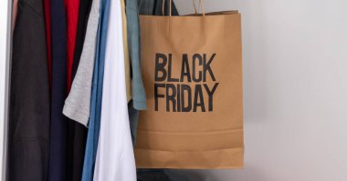 Black friday shopping bag with clothes with clothes hanger inside wardrobe , also with mock up space clipart