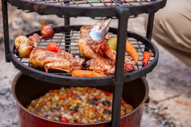 Zurbian dinner. The barrel has been uncovered and it is ready and well cooked. It contains chicken, vegetables and rice. It is placed on a wire rack and it has been transferred to the serving tray. clipart