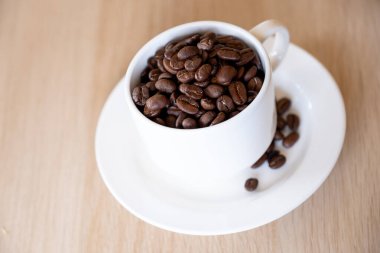 Kahveyle dolu bir fincan kahve. Ahşap zemin üzerinde, hafif kahve.