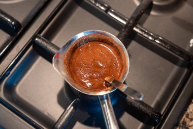Siyah gaz ocağında kahve demliği kaynamaya hazır.