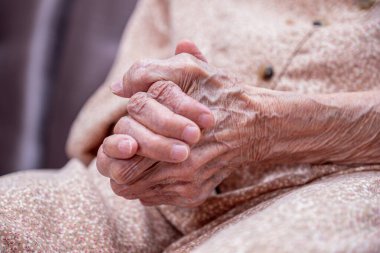 Yaşlı kadın elleri kırış kırış, kocası olmadan kendini yalnız hissediyor.