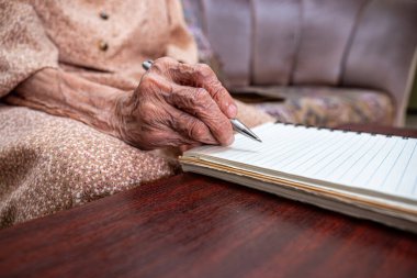 Yaşlı birinin not defterine notlar yazması için buruşuk eller.