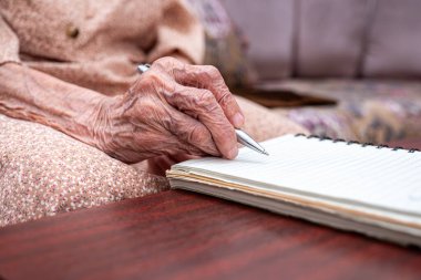 Yaşlı birinin not defterine notlar yazması için buruşuk eller.