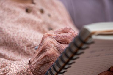Yaşlı birinin not defterine notlar yazması için buruşuk eller.