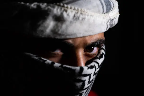 stock image portrait of pearson wearing white keffiyeh on dark background with anger expression on his eyes due to violence and against occupation