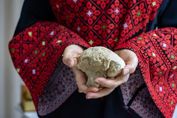 Filistinli bir kadın elinde, işgale karşı koyabilecek tek silahı temsil eden bir taş tutuyor.