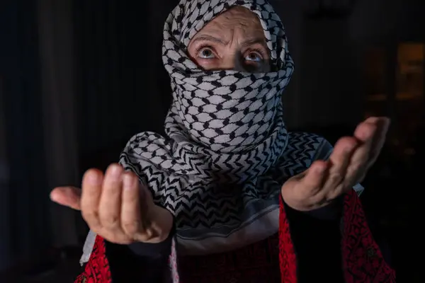 stock image portrait for person praying to allah with white keffiyeh on his face in dark background