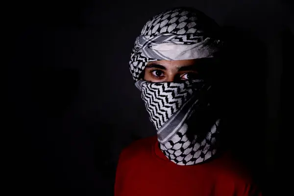 stock image portrait of pearson wearing white keffiyeh on dark background with anger expression on his eyes due to violence and against occupation