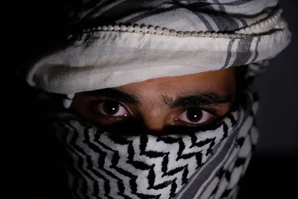 stock image portrait of pearson wearing white keffiyeh on dark background with anger expression on his eyes due to violence and against occupation