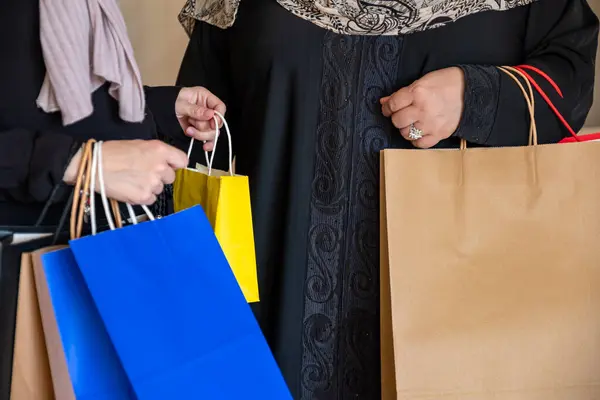 Stock image Arabic woman gifting her mother and showing the new clothes after shopping with shopping bags in the background in living room