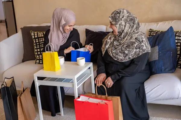 stock image Arabian woman in living room with her mother  checking shopping bags after shopping and providing gift to her mother