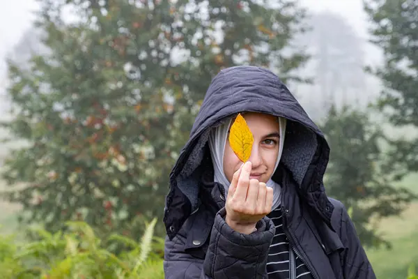 stock image Arabian female holding yellow leaf during autumn representing transition period between winter and autumn seasons