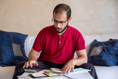 Vergi, elektrik, su, yiyecek ve içeceklerin faturalarını hesap makinesiyle hesaplayan adam