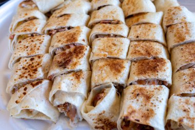 Tahta masada soslu shawarma parçaları var ve beyaz tabağa dizilmiş.