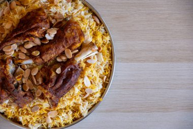 Tahta masadaki üst manzaralı bademlerle kaplı et ve pirinç tabağı.
