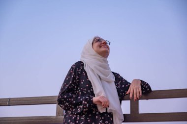 female wearing hijab and islamic wears having vacation in resort with smile on their face and beautiful blurred lights in the background clipart