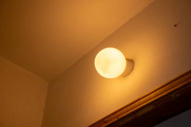 Sarı tungsten lamba kapının üstündeki duvarda asılı.