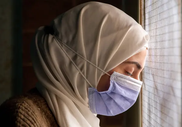 Müslüman kadın maske takıyor ve Allah 'a kendisini hastalıklardan koruması için dua ediyor.