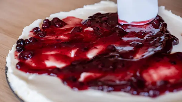 stock image preparing cheesecake with red syrup of red berries and strawberries with cheesecake pan