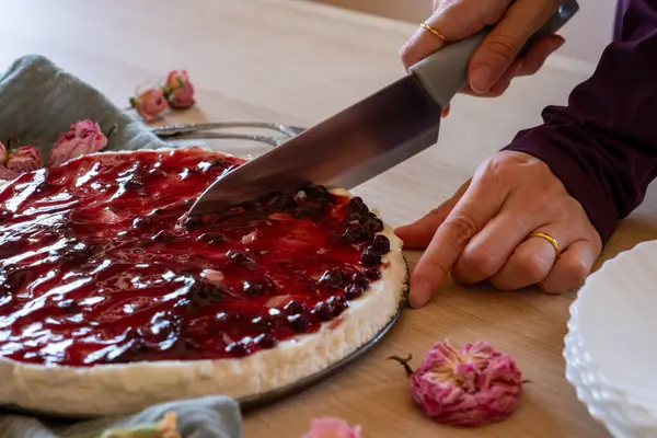 stock image hands slicing cheesecake on wooden background with roses around