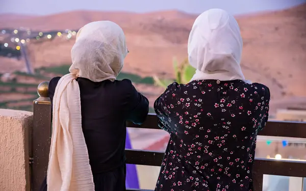 Stock image Two females wearing hijab and islamic wears having vacation in resort with smile on their face and beautiful blurred lights in the background