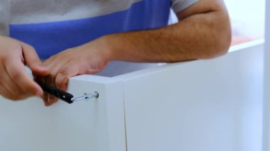 Erkek eller beyaz ahşap tahtayı içeride birleştiriyor. Kendi mobilyalarını inşa ediyor ve onarıyor. Büyülü anahtar ve Allen anahtarıyla.