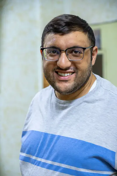 stock image Man in glasses, smiling and relaxed at home, captured in candid portraits. Sitting on an armchair, wearing casual shirts. Perfect for lifestyle and everyday moments themes
