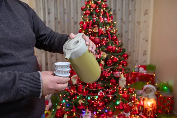 stock image Arab male puring arabic coffee in the cup for guests while a christmas tree is in the background celebrating holiday with relatives