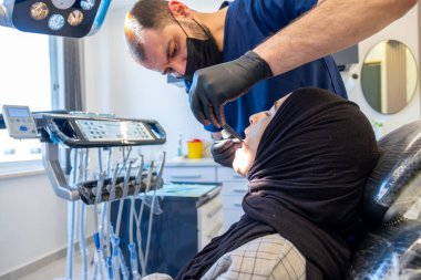 Klinikteki tıbbi ekipmanlarla hastayı muayene eden dişçi.