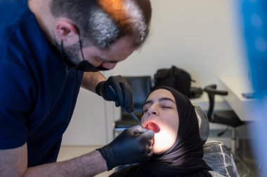 Dişçi koltuğundaki müslüman kadının diş ağrısı için tedaviye ihtiyacı var.