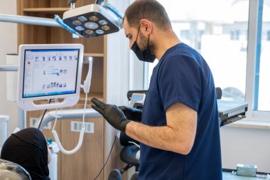 Diş hekimi ve Müslüman kadın arasında yapılan konuşma ekrandaki diş röntgenine bakarak ve doktor bu tür bir hastalık ve diş ağrısından kaçınmak için tedavi planını anlatıyor.