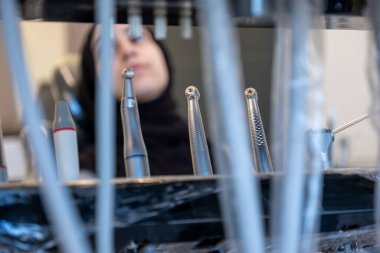 İnceleme ya da tedavi seansı sırasında dişçi koltuğunda, matkaplar ve pullar da dahil olmak üzere diş aletleri odaklı bulanık bir kadın hasta