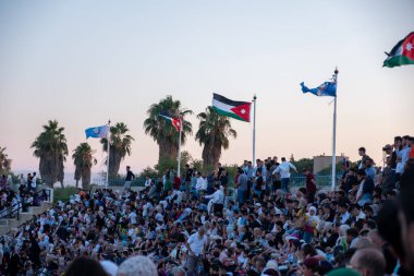 Stadyum sandalyelerinde izleyiciler mezuniyet kutlamalarını izliyorlar. Aileleri ve akrabaları için el sallıyorlar, onlar için seviniyorlar. (Jordan, 24 Temmuz 'da Ürdün Bilim ve Teknoloji Üniversitesi)