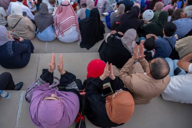 Bir sürü insan stadyum sahnesinden mezun olan öğrencileri izliyor.