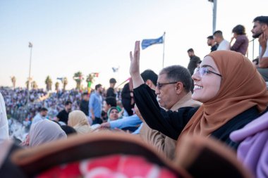 Arap Ailesi, oğullarının mezuniyetini seyrediyor ve sahnede onun için el sallıyor.