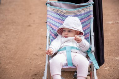 Parlak bir günde bebek arabasında neşeli bir bebek, doğanın güzelliğiyle çevrili, sevgiyi, masumiyeti ve çocukluk sevincini gösteren