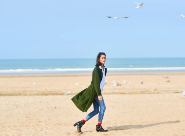 Kumsalda ceketli genç bir kadın.