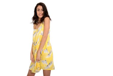 Beyaz arka planda sarı yaz elbisesi içinde gülümseyen esmer bir kadın.