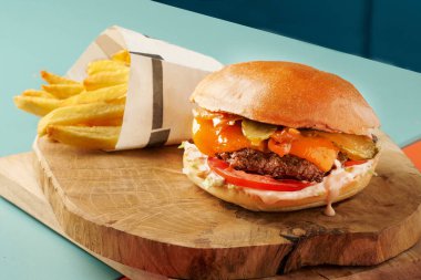 Kırmızı soğan ve patates kızartmalı Cheddar Hamburger.