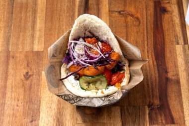 Pita parçalanmış domuz eti, aioli, organik zeytinyağı, turşulu kırmızı lahana, soğan ve vişne domatesli tatlı patates ve sebze.