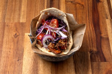 Pita yavaş pişirilmiş domuz eti, aioli, organik zeytinyağı, turşulu kırmızı lahana, soğan ve vişneli domatesle kızartılmış tatlı patates ve sebze.