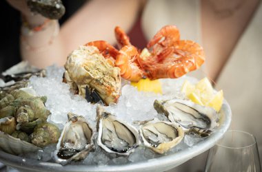 Buz yatağında deniz ürünleri tabağı, istiridye, karides, yengeç ve limon.