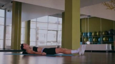 Güzel bir vücudu olan, boş, aydınlık bir odada egzersiz yapan sportif bir kadın. Spor kıyafetleri giymiş spor salonunda esneme hareketleri yapan bir kız antrenör. Büyük, havadar bir uzay spor salonunda spor yapan bir sporcu..