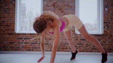Güzel bir vücudu olan, boş, aydınlık bir odada egzersiz yapan sportif bir kadın. Spor kıyafetleri giymiş spor salonunda esneme hareketleri yapan bir kız antrenör. Büyük, havadar bir uzay spor salonunda spor yapan bir sporcu..
