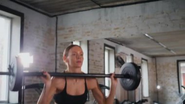 Spor salonunda halterle çömelmiş bir kadın. Spor meraklısı ağırlıklarla çömelme hareketi yapıyor. Güçlü kadın antrenmanda halter kaldırıyor. Spor salonunda halterle egzersiz yapan bir kadın. Kadın spor salonunda çekirdek egzersizi yapıyor. Spor salonundaki spor meraklısı.. 