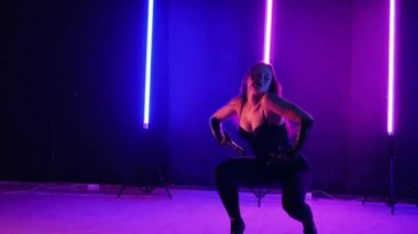 Neon ışıklarının altında dans eden kadın silueti. Canlı neon ışıklı dans pisti ve hareket halindeki bir kadın. Karanlık odada neon parıltısıyla enerjik bir dans gösterisi. Kendinden geçmiş kadın dansçı. Siyah elbiseli zarif bayan parlak neon ışıkların önünde poz veriyor..