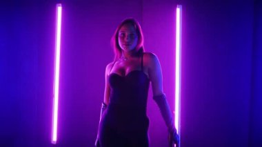 Neon ışıklarının altında dans eden kadın silueti. Canlı neon ışıklı dans pisti ve hareket halindeki bir kadın. Karanlık odada neon parıltısıyla enerjik bir dans gösterisi. Kendinden geçmiş kadın dansçı. Siyah elbiseli zarif bayan parlak neon ışıkların önünde poz veriyor..