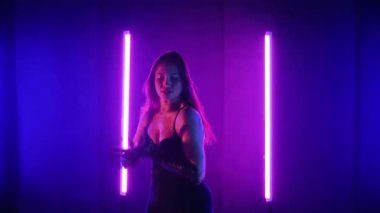 Neon ışıklarının altında dans eden kadın silueti. Canlı neon ışıklı dans pisti ve hareket halindeki bir kadın. Karanlık odada neon parıltısıyla enerjik bir dans gösterisi. Kendinden geçmiş kadın dansçı. Siyah elbiseli zarif bayan parlak neon ışıkların önünde poz veriyor..