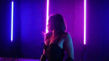 Neon ışıklarının altında dans eden kadın silueti. Canlı neon ışıklı dans pisti ve hareket halindeki bir kadın. Karanlık odada neon parıltısıyla enerjik bir dans gösterisi. Kendinden geçmiş kadın dansçı. Siyah elbiseli zarif bayan parlak neon ışıkların önünde poz veriyor..