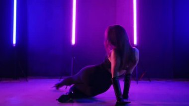 Neon ışıklarının altında dans eden kadın silueti. Canlı neon ışıklı dans pisti ve hareket halindeki bir kadın. Karanlık odada neon parıltısıyla enerjik bir dans gösterisi. Kendinden geçmiş kadın dansçı. Siyah elbiseli zarif bayan parlak neon ışıkların önünde poz veriyor..